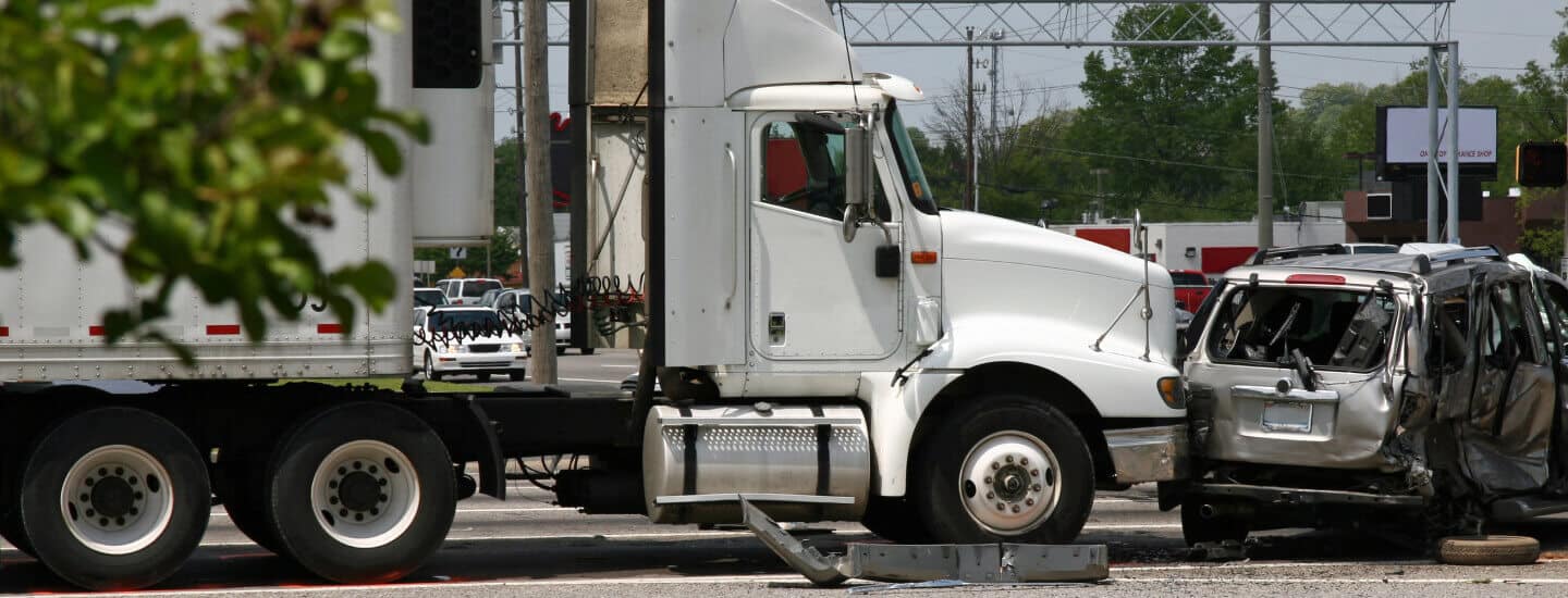 Image of an automobile accident between semi truck and car.