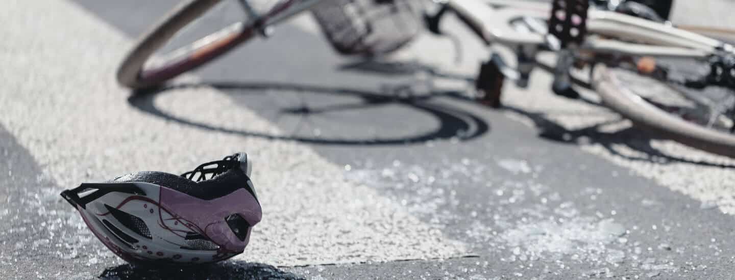 A close up of a bicycle accident with a helmet on the ground